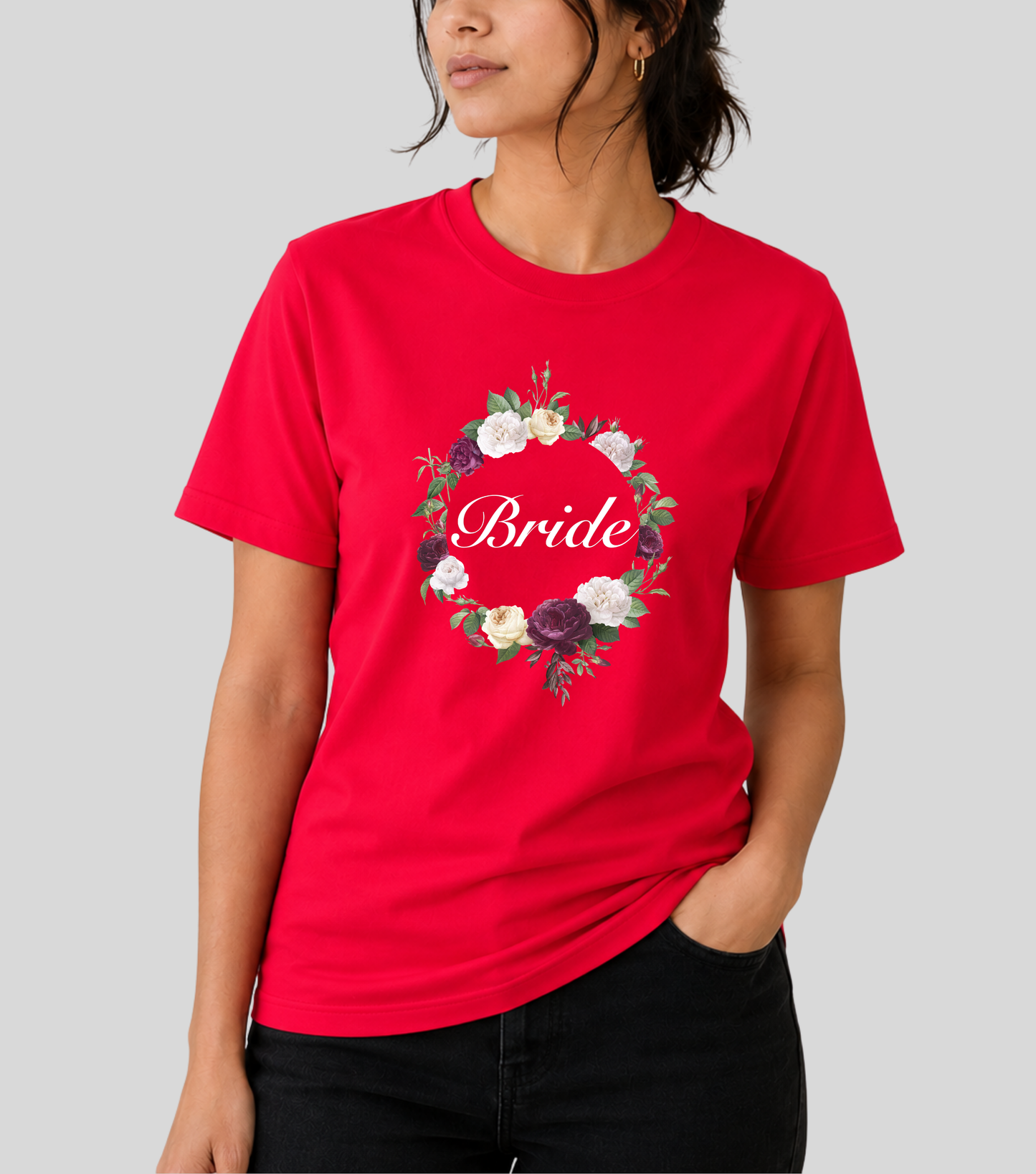 A woman wearing a bright red short-sleeve t-shirt with a floral wreath graphic and the word 'Bride' in white script across the chest, paired with black pants, against a solid gray background.