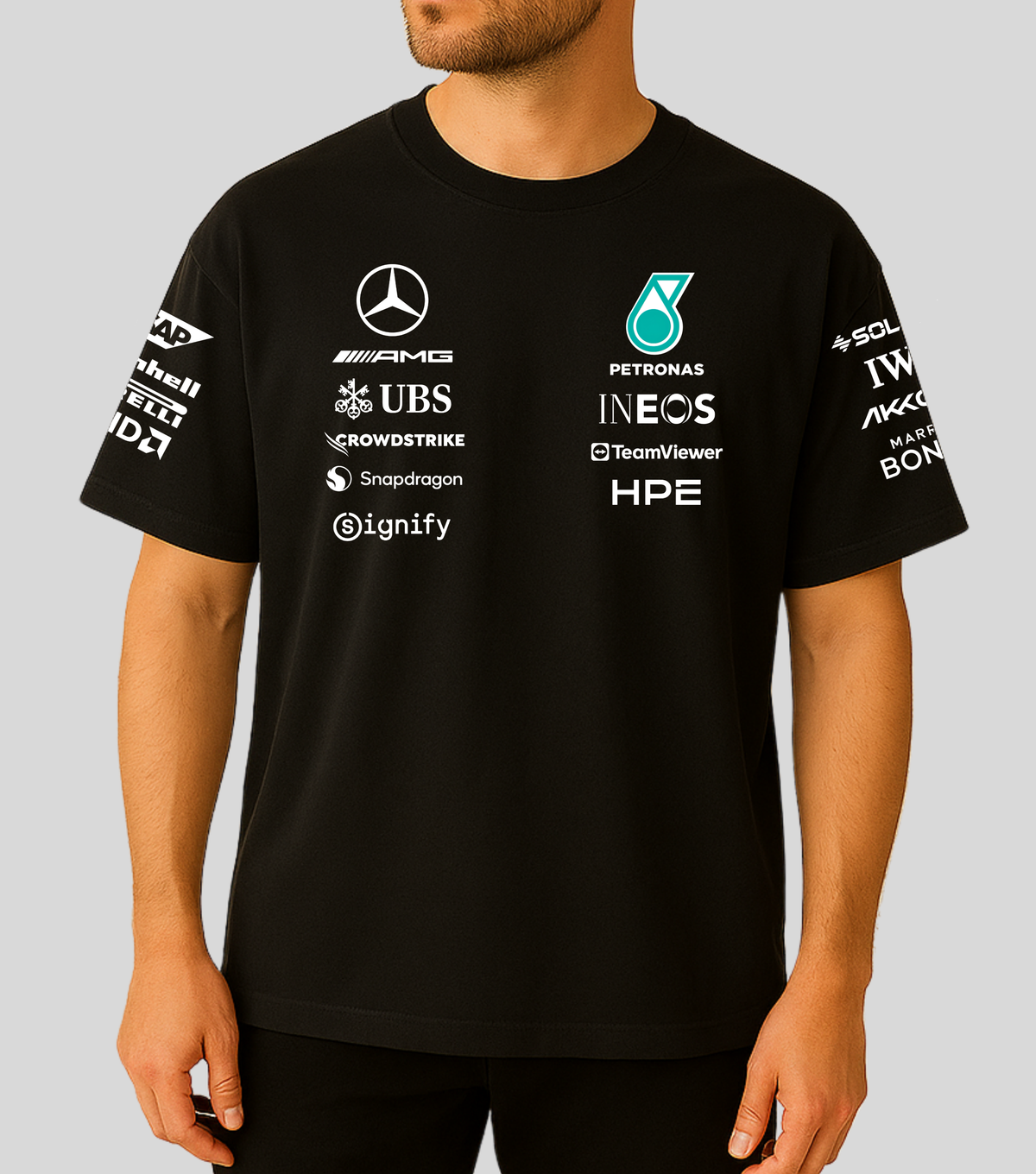 A man wearing a black Mercedes Petronas Formula 1 team t-shirt with various sponsor logos printed in white and teal on the front and sleeves.